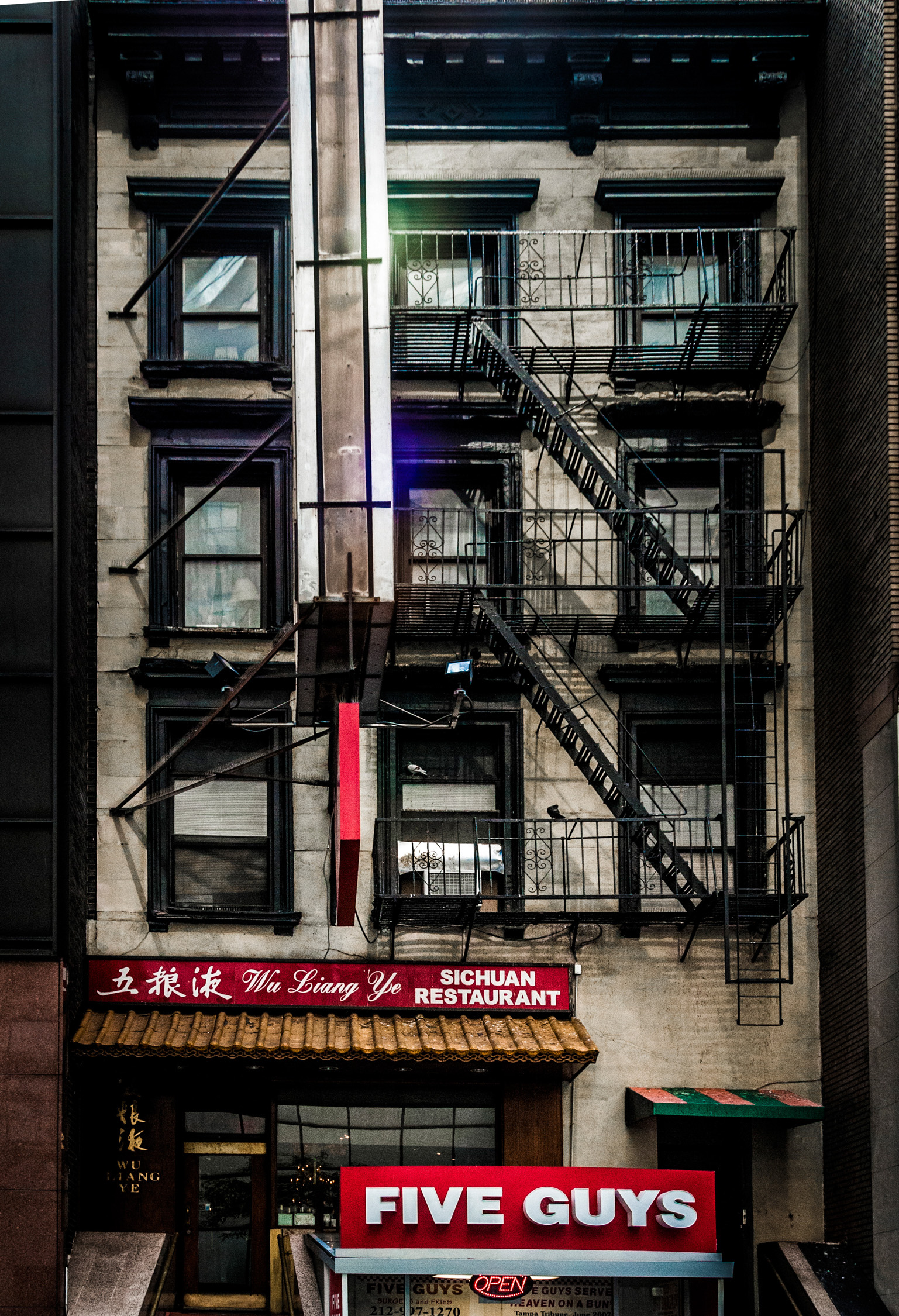 Vertical lines of next-door buildings framing the diagonal lines of the fire escapes